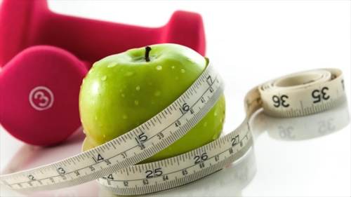 Apple wrapped in a tape measure with pink weights