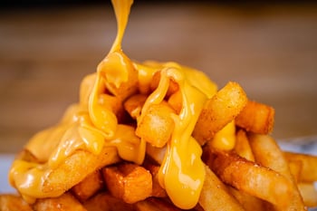 Fries being covered by cheese sauce