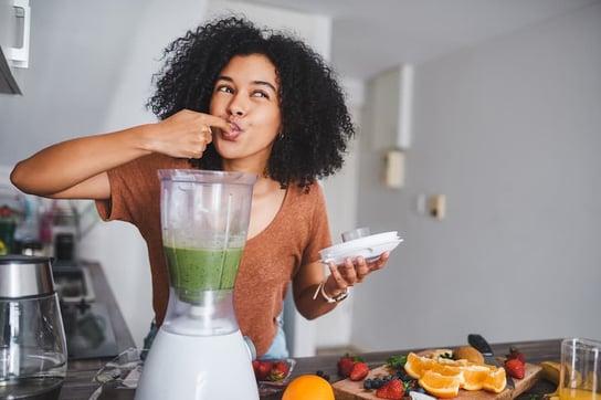 Person in a good mood tasting smoothie from blender