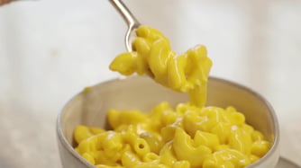 Mac and cheese being removed with a fork from a bowl